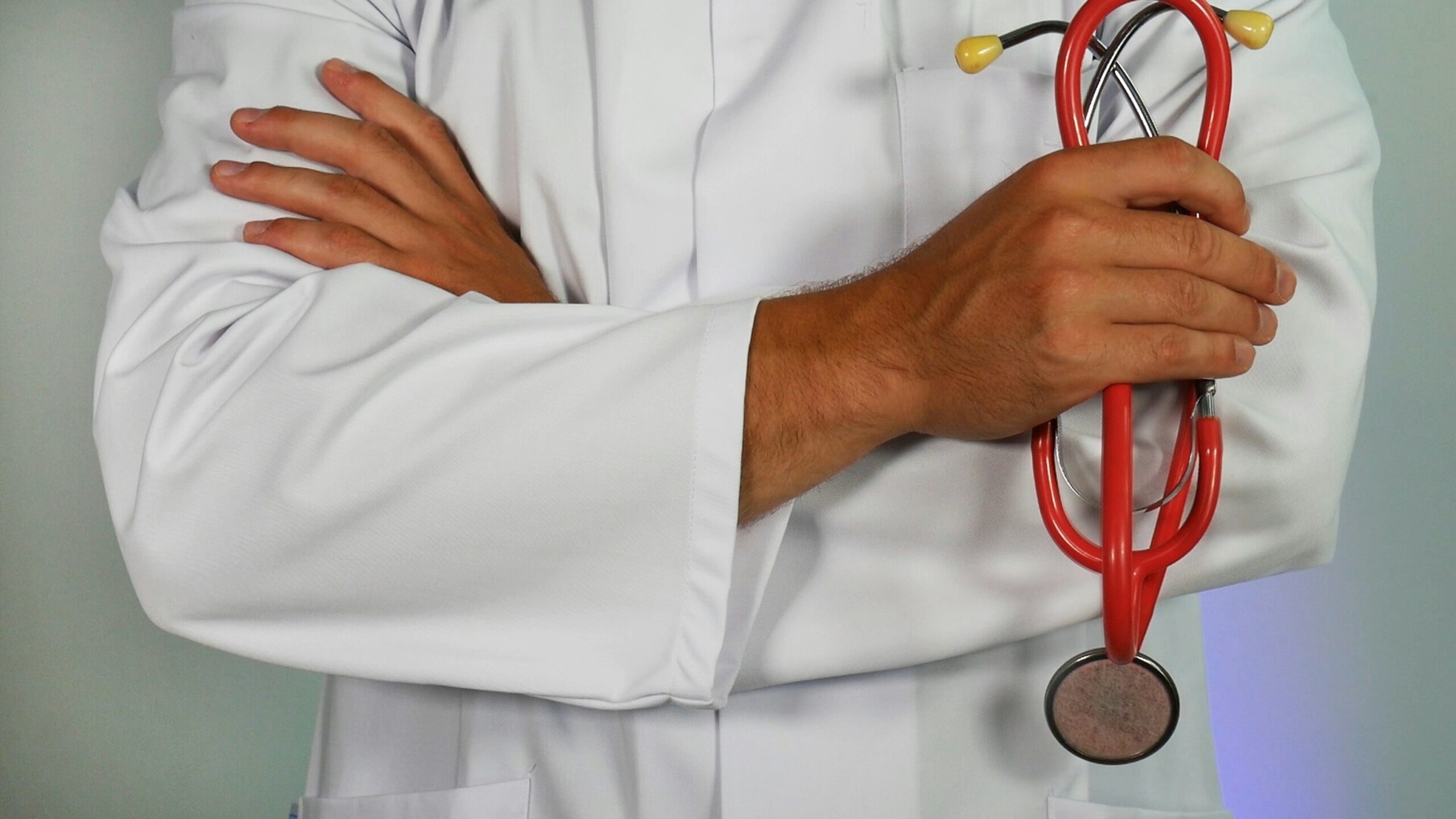 Doctor holding a red stethoscope while folding his arms.